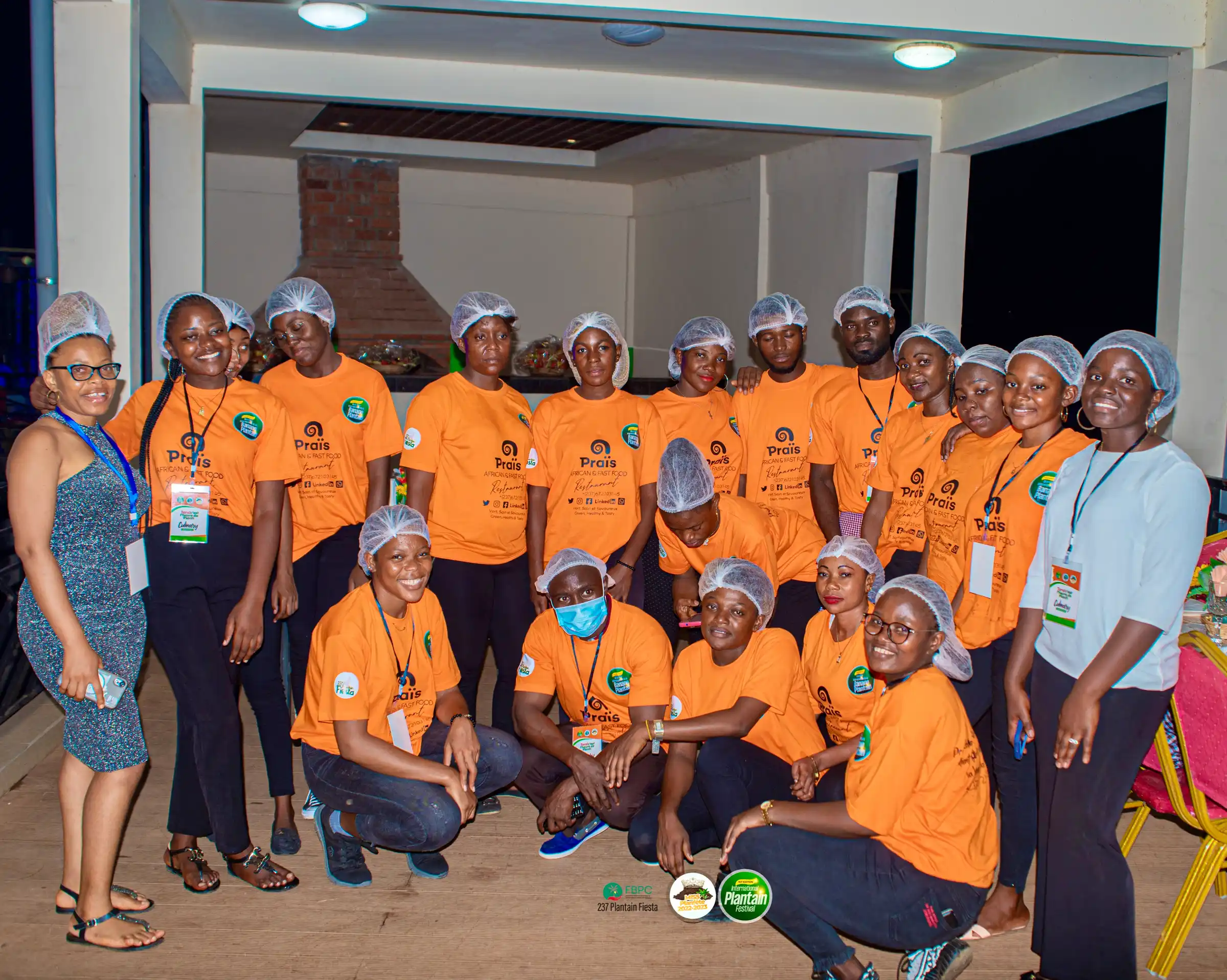 A training group in orange T-shirts and hairnets, posing together