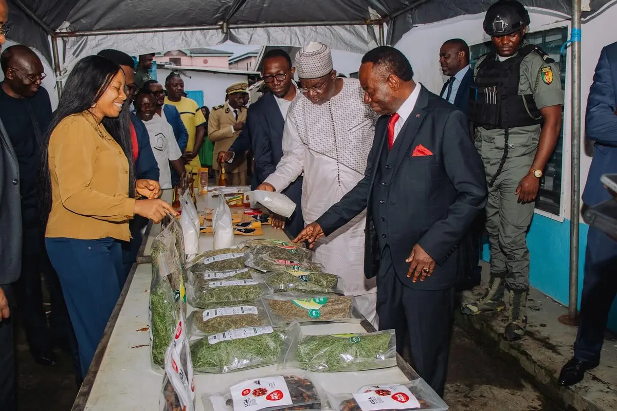 Officials in suits look over Mumita products laid out on a long table
