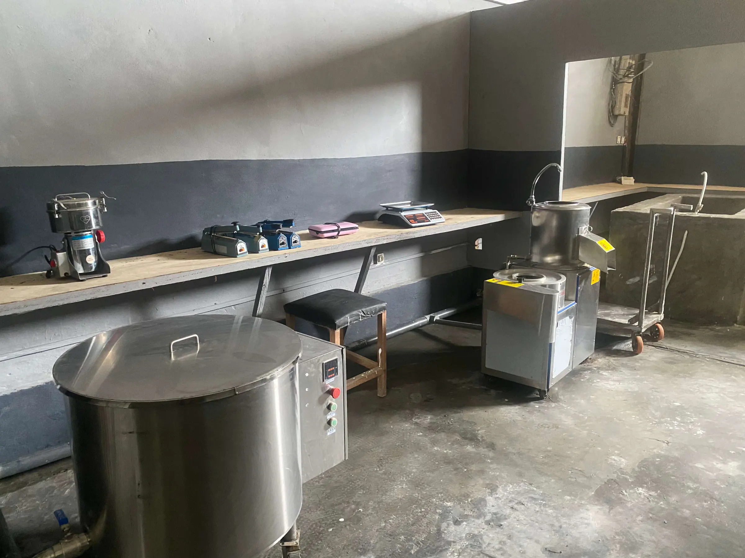 A fitted processing room with a stainless steel cooking vat, a mill and benches