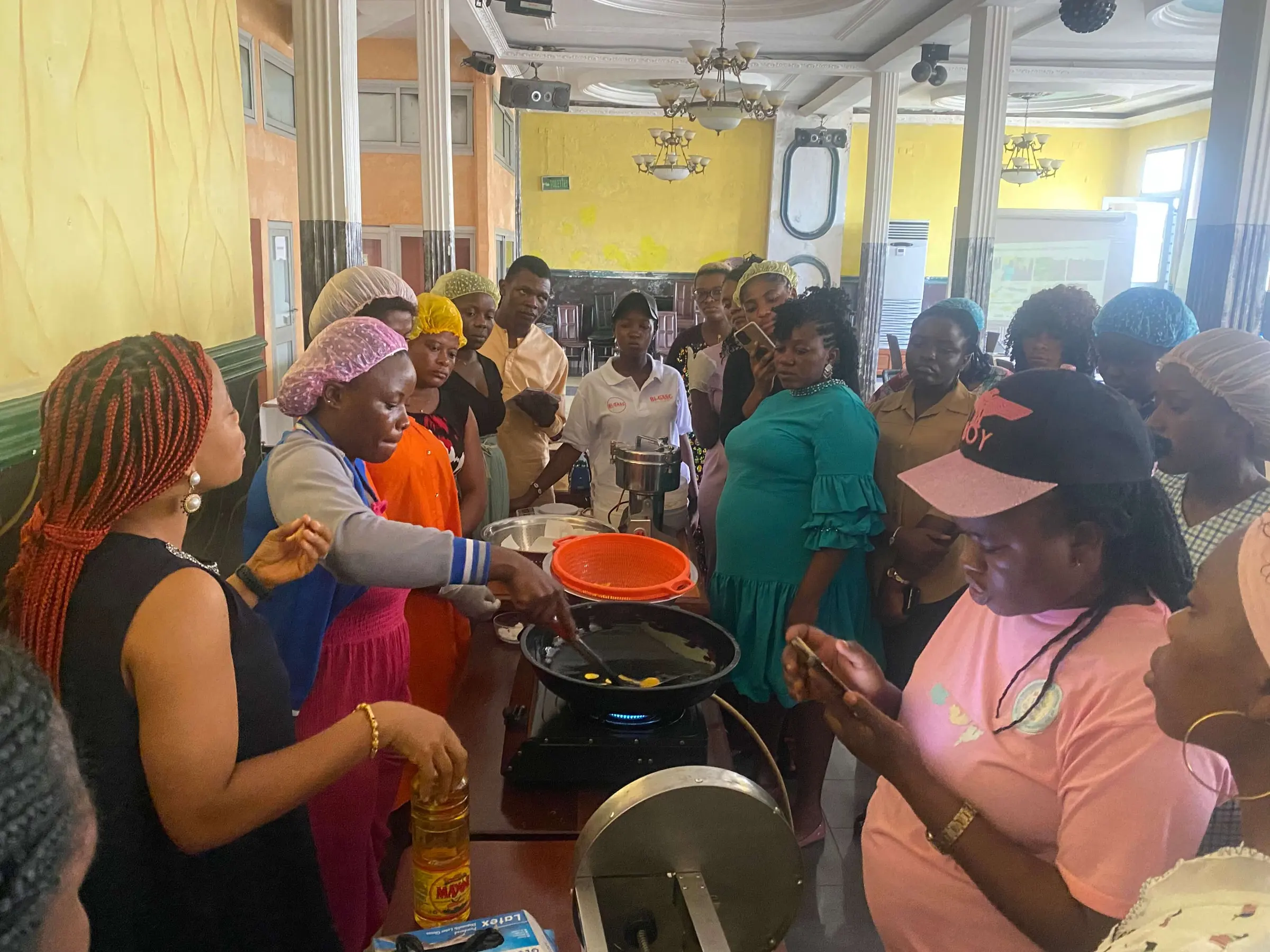 Participants in hairnets crowding round a cooking demonstration