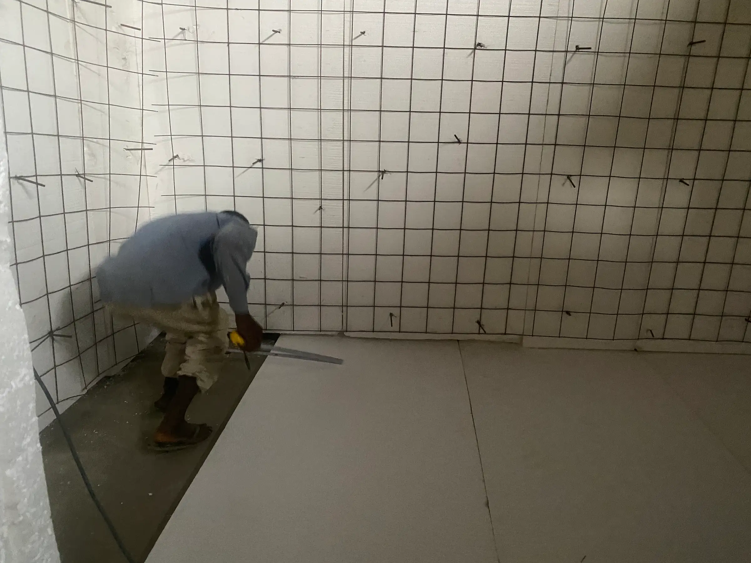 A worker fits white wall panels in a bare, unfinished room at the Bonduma Gate facility