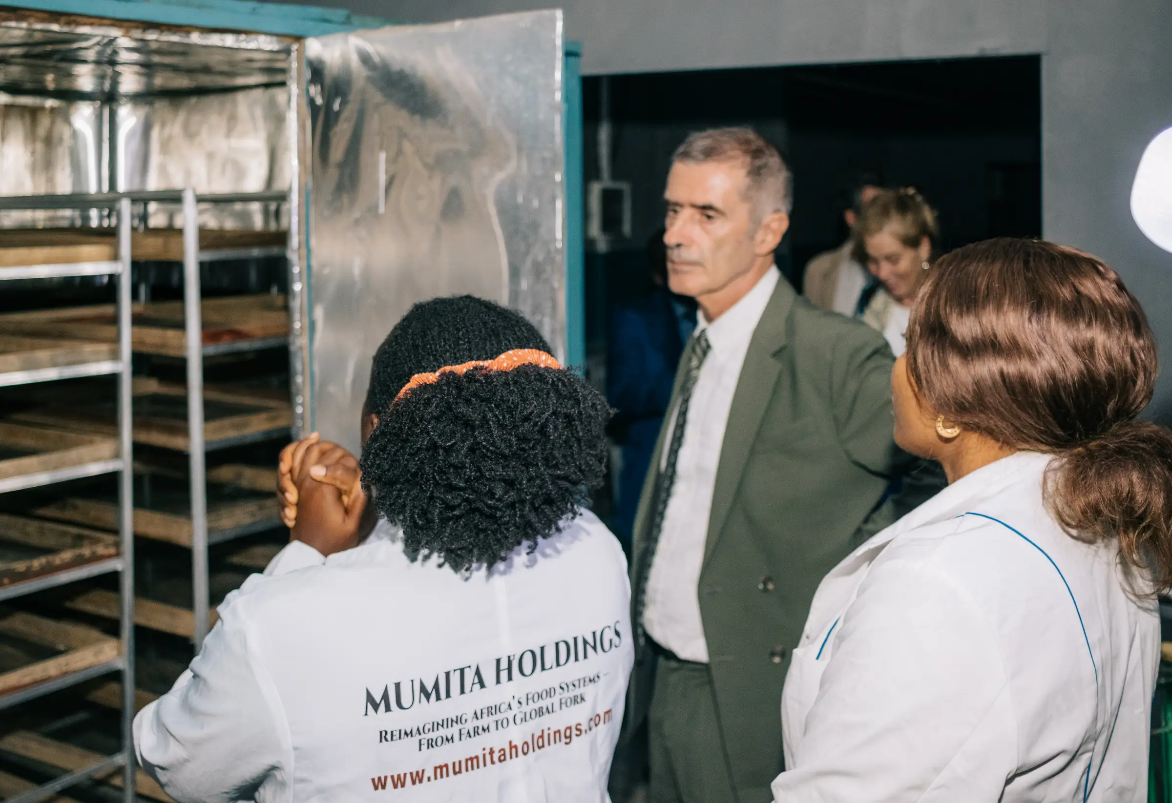 A Mumita staff member beside the drying cabinet with visitors