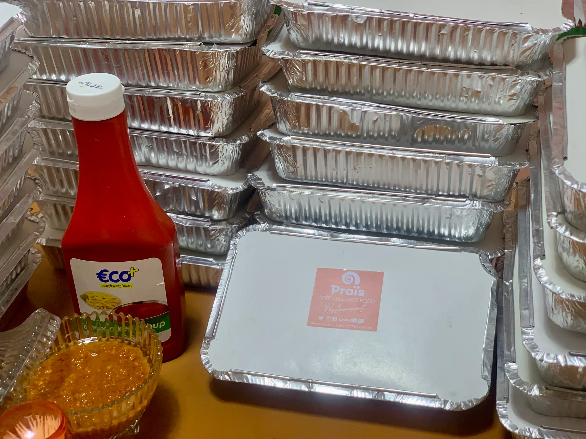 Praïs-labelled catering trays stacked for delivery
