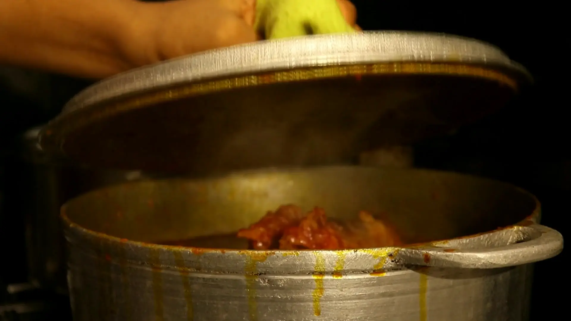 In the Praïs kitchen, a lid comes off a pot of red stew and a spoon stirs it